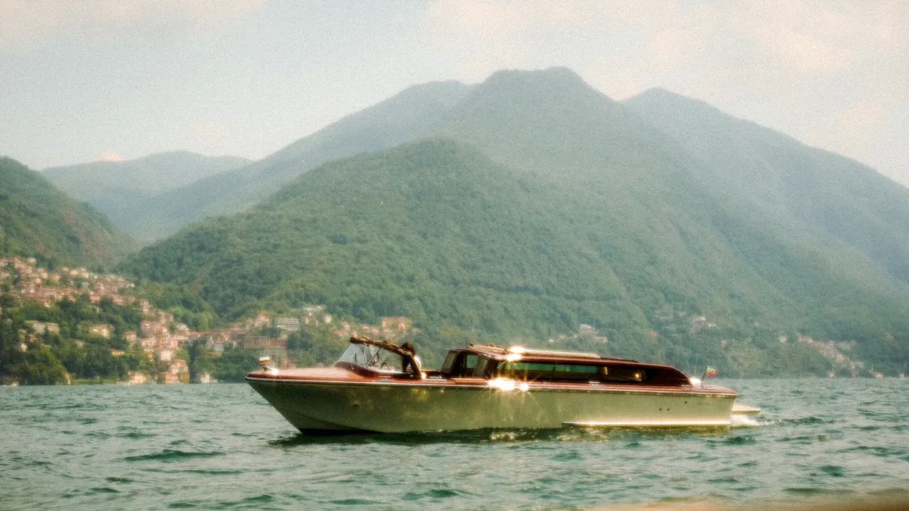 A wooden Venetian taxi boat under way on Lake Como below the mountains.