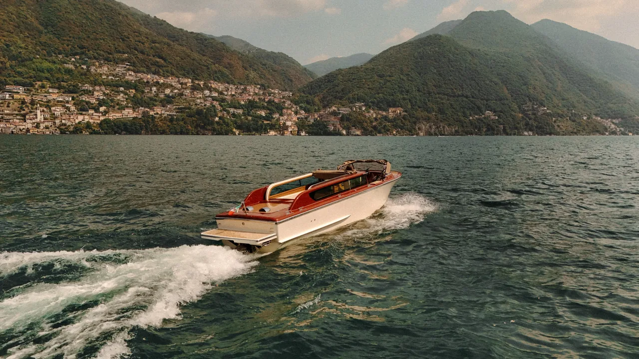 Lake Como seen wide, with the boat on the water and the villages along the shore.