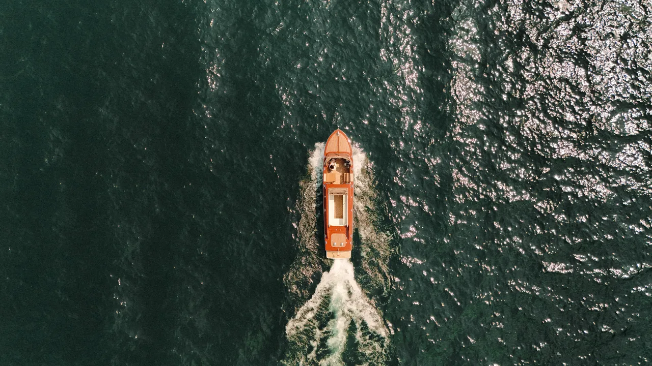 The boat crossing the open water of Lake Como, seen from above.